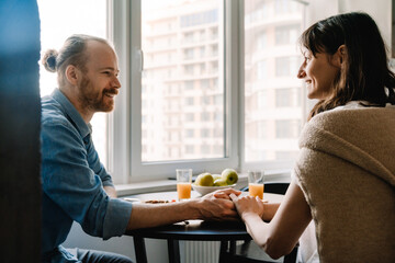 Young white couple smiling while having breakfast together at home