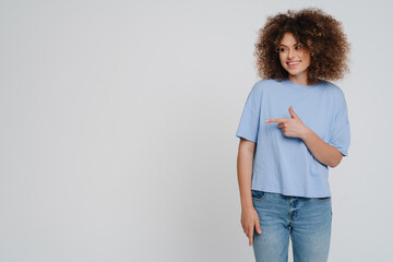 Young beautiful smiling curly woman looking and pointing aside