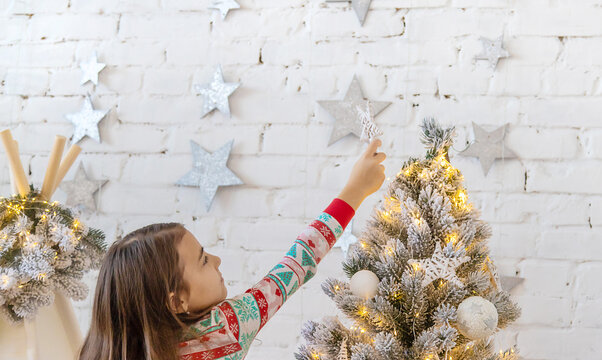 A child hangs a star on a Christmas tree. Selective focus.