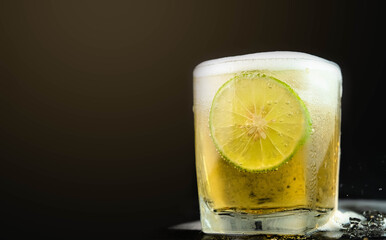 Shot of golden Mexican tequila with lime and salt on black background. A glass of tequila with lemon slices and splashing. Alcoholic drink concept. selective focus.