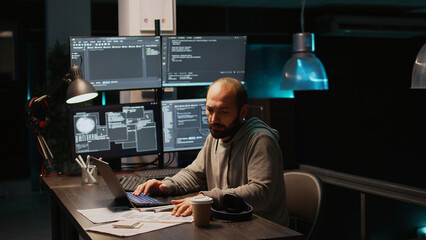 Software engineer typing source code on multiple monitors, displaying terminal window with html...
