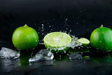 Fototapeta na wymiar Water drops on lemon slices and splash with ice cubes on table on black background. selective focus.