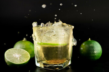 Shot of golden Mexican tequila with lime and salt on black background. A glass of tequila with lemon slices and splashing. Alcoholic drink concept. selective focus.