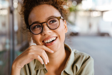 Hispanic woman in eyeglasses smiling while sitting at cafe