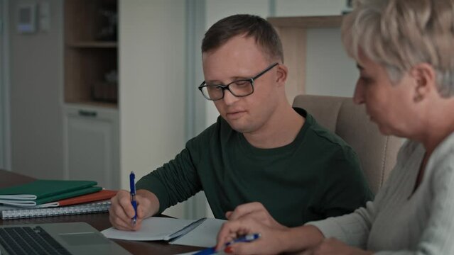 Caucasian man with down syndrome learning with his mum at home. Shot with RED helium camera in 8K.   