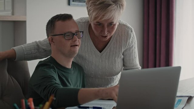 Caucasian man with down syndrome learning with his mum at home. Shot with RED helium camera in 8K.    