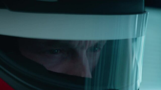 ECU Portrait of sports car driver in protective helmet racing on a speedway. Fast speed, motorsport. Daytime shot