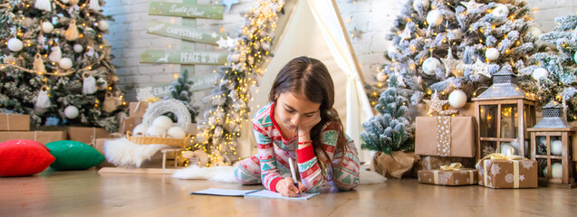 Children write a letter to Santa under the tree. Selective focus.