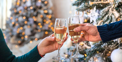 Man and woman with champagne in their hands near the Christmas tree. Selective focus.