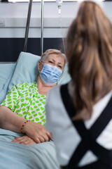 Unrecognizable little girl talking to grandmother at hospital. Old lady enjoying the company of...