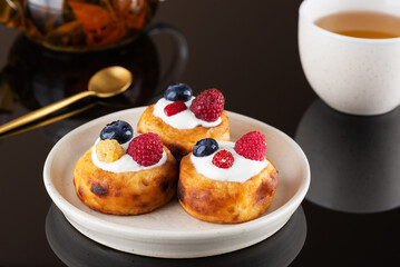 Breakfast cheese pancakes with blueberries, raspberries and sour cream with cup of tea.