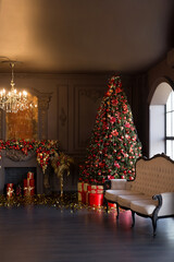 Interior of luxury dark living room with fireplace, comfortable sofa and chandelier decorated with Christmas tree and gifts