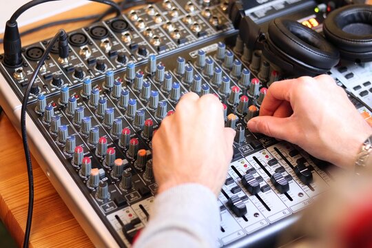 Get a taste of the music industry with our photo of a man using an audio mixer. This image captures the essence of sound engineering and the creation of music. 