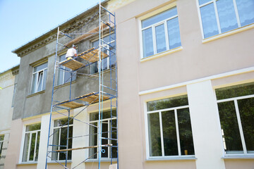 Builder contractor plastering external walls before painting outside house facade. Prepare for...