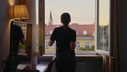Woman standing at a hotel or apartment window dancing and enjoying the moment. During a trip vacation or holiday a tourist or young female traveler having fun and energy dancing funny in room