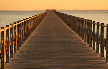 Naklejka premium A wooden pontoon deck on a sea side beach during summer sunrise.