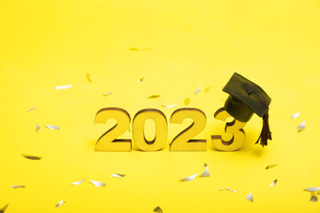 Class of 2023 concept. Numbers 2023 with black graduated cap on yellow background.