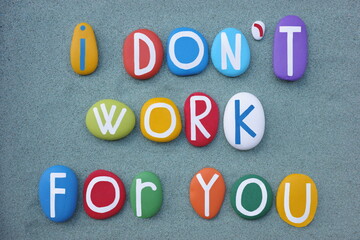 I do not work for you, creative slogan composed with multi colored stone letters over green sand