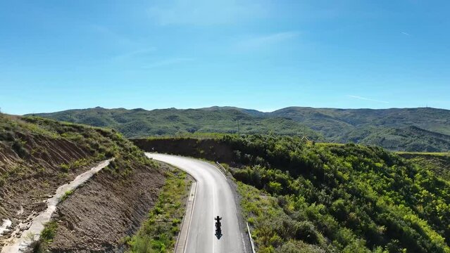 Biker riding alone on an empty road in the hills during daylight
