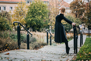 Ballerina Dancing in autumn city street, Modern Ballet Dancer in black dress, Pointe Shoes outdoors. Ballerina stretches, daily ballet stretching routine © irissca