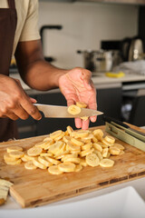 Unrecognizable young african man cutting plantains in a kitchen.