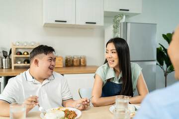 Asian happy family, mature parent having breakfast with son in kitchen. 