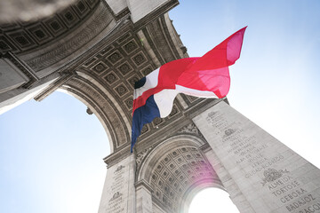 Wide angle photo with the National Flag of France waving under the Arch of Triumph landmark building during Armistice Day. - obrazy, fototapety, plakaty
