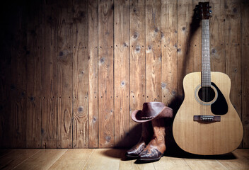 Acoustic guitar, cowboy hat and boots against blank wooden plank panel grunge background with copy space - 545894736