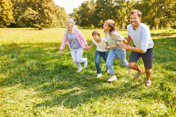 Naklejka na ściany i meble Happy family runs across a green meadow