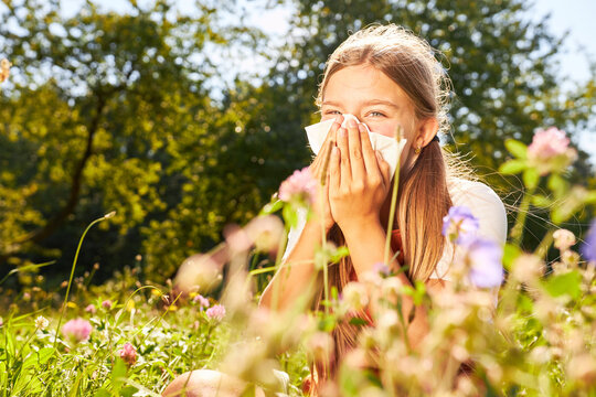 Girl sneezing with hay fever in meadow