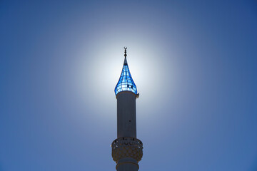 Architecture of an Islamic mosque in Turkey against the backdrop of a sunny sky background. Minaret of a Muslim mosque with a blue dome