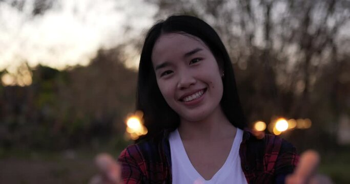 Asian beautiful woman holding fireworks burning sparkler playing in New year festival, Dressed in plaid shirt, waving hands, smiling and looking at the camera, she enjoy on new year's party night