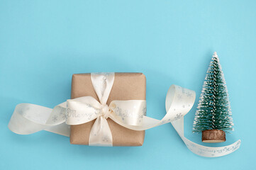 Christmas gift box and miniature Christmas tree on a blue background. Holiday greeting card.