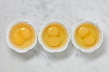 Double yolk eggs in a bowl on a white marble surface. Two yolks in one chicken egg. Identical twins. Double eggs.