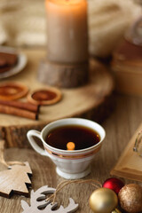Fototapeta premium Cup of tea or coffee, various sweets and spices, Christmas decorations, comfy blanket, books and glasses. Selective focus.