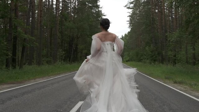 The bride runs along the road and her dress develops