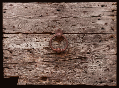 Detail einer historisch alten Tür aus verwitterten Holz mit rostigen Türklopfer