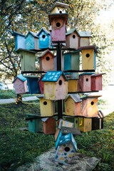 welcome to the spring garden birds to a group of colorful wooden birdhouses on a blue sky background