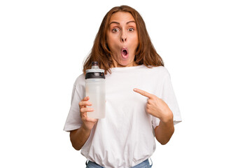 Young caucasian sport woman holding a bottle of water isolated pointing to the side