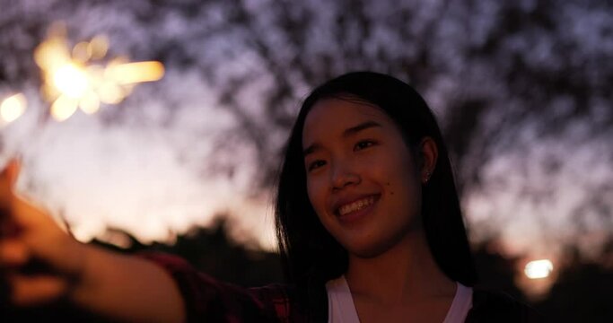 Selective focus, Asian beautiful woman holding and looking a fireworks burning sparkler in New year festival, smile with enjoy on new year's party night