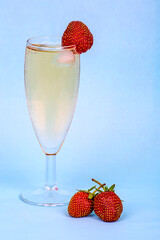 A misted glass of champagne and fresh strawberries on a blue background