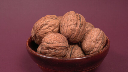 Closeup photo of a walnut seed in wooden bowl. Food that is good for brain and lower risk of heart disease.