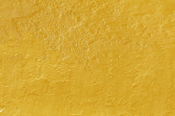 Gold paint on rough cement wall texture.