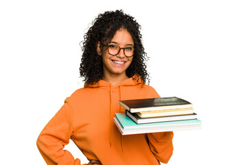 Young student woman holding a pile of books isolated showing a copy space on a palm and holding...