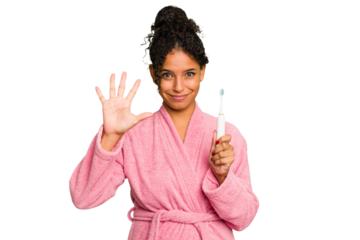 Young brazilian woman holding an electric toothbrush isolated smiling cheerful showing number five with fingers.