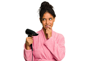 Young brazilian woman wearing a pink bathrobe holding an hairdryer isolated relaxed thinking about something looking at a copy space.