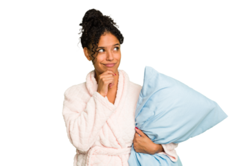 Young brazilian woman wearing a pajama holding a pillow isolated looking sideways with doubtful and skeptical expression.