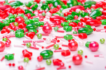 Christmas background of colorful candies. Red and green candies of different shapes on a light background, macro photography