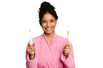 Young african american woman doing a comparison between a normal toothbrush and electrical isolated from background