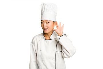 Young asian cook woman isolated trying to listening a gossip.